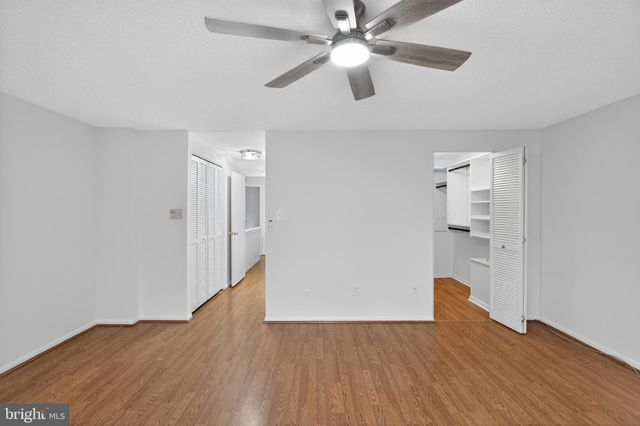 a view of empty room with wooden floor and ceiling fan