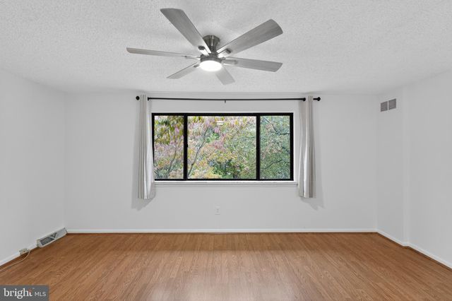 an empty room with wooden floor fan and windows