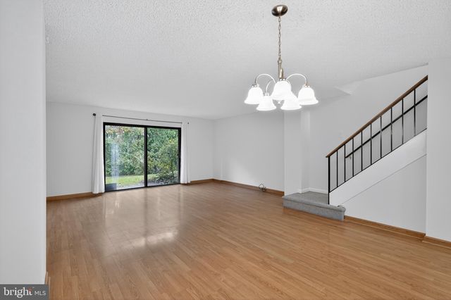 a view of an empty room with wooden floor and a chandelier