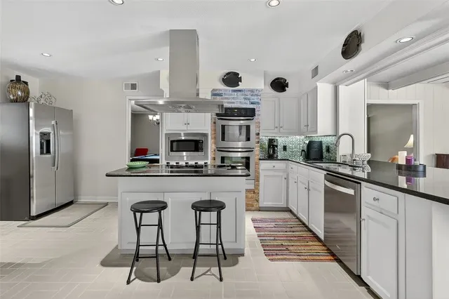 a kitchen with stainless steel appliances granite countertop a stove top oven a sink dishwasher and a refrigerator