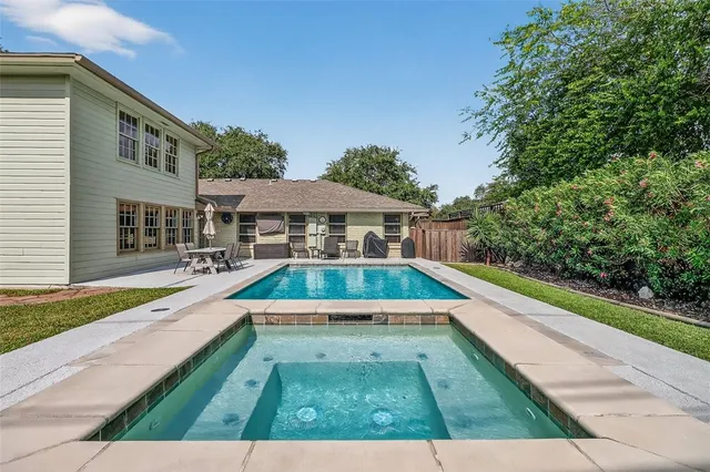 a view of swimming pool with lawn chairs and plants