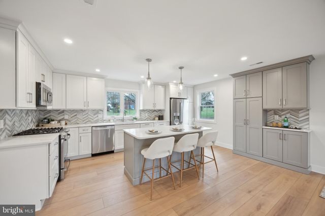 a kitchen with a sink a stove a refrigerator and white cabinets with wooden floor