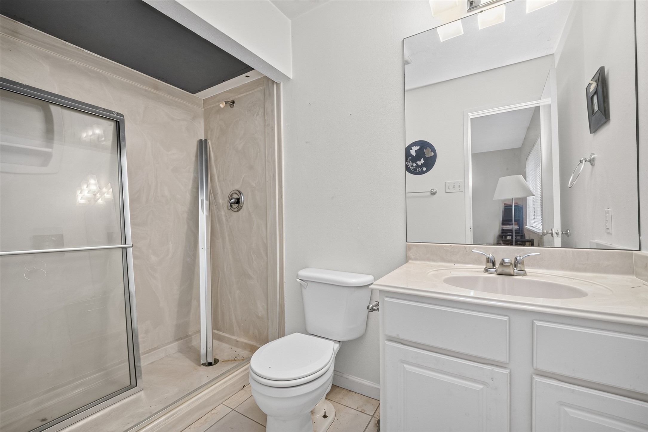 22926 Millgate Drive Spring, TX 77373 - Photo 27 of 34 This bathroom features a sleek, modern design with a glass-enclosed shower, a white vanity with a mirror, and neutral tile flooring.