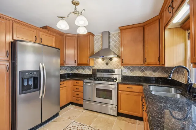 a kitchen with stainless steel appliances granite countertop a stove a refrigerator and a sink