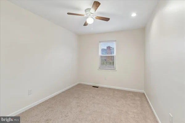 an empty room with a chandelier fan and windows