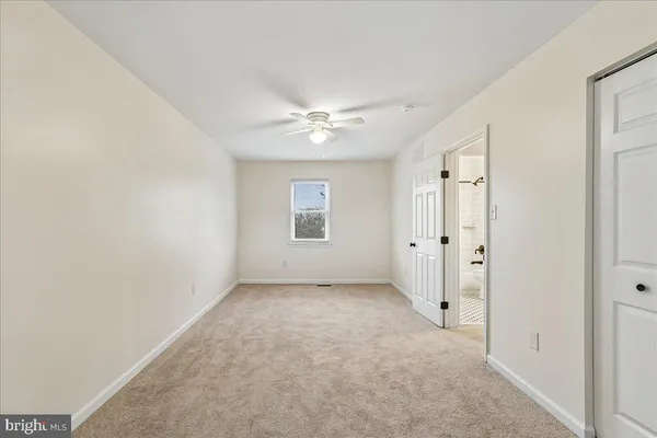an empty room with a ceiling fan and a window