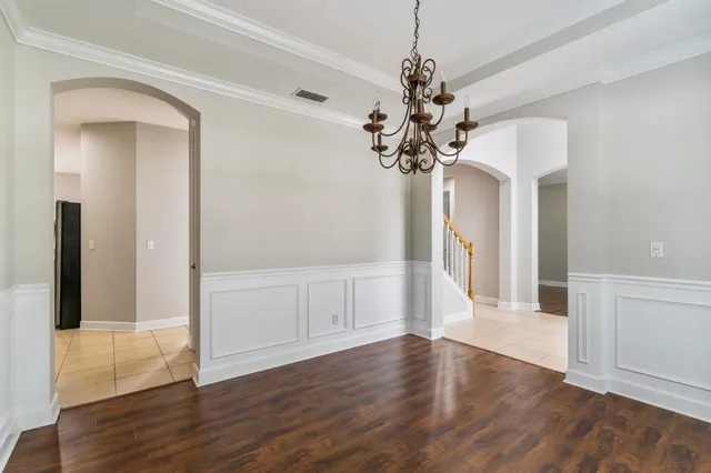 a view of a hallway with wooden floor and a chandelier