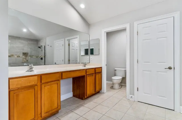 a spacious bathroom with a double vanity sink a large mirror and a toilet
