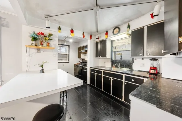 a kitchen with granite countertop a sink a stove and chairs