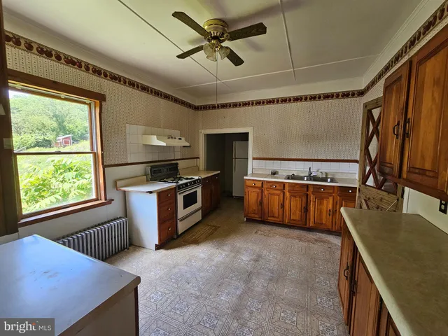 a kitchen with stainless steel appliances granite countertop a sink a stove top oven a chimney cabinets and a counter top space