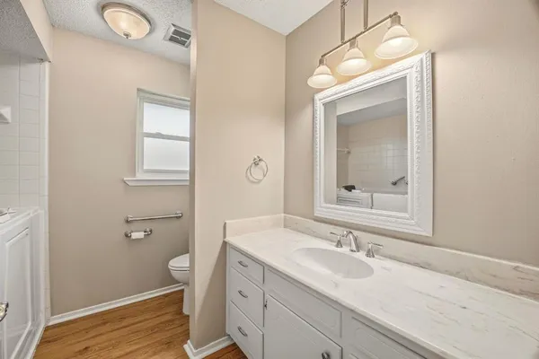 a bathroom with a granite countertop sink a toilet and a mirror