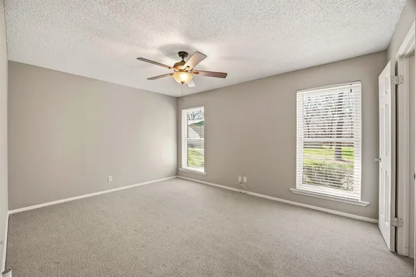 an empty room with windows and ceiling fan