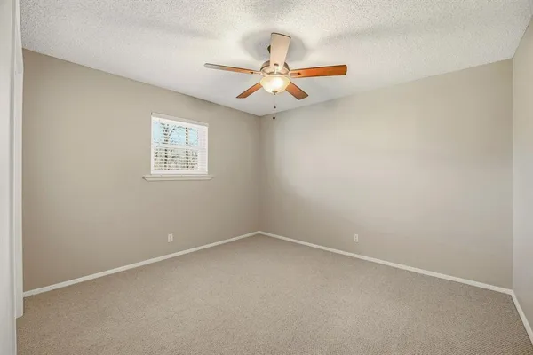 an empty room with a window and a fan