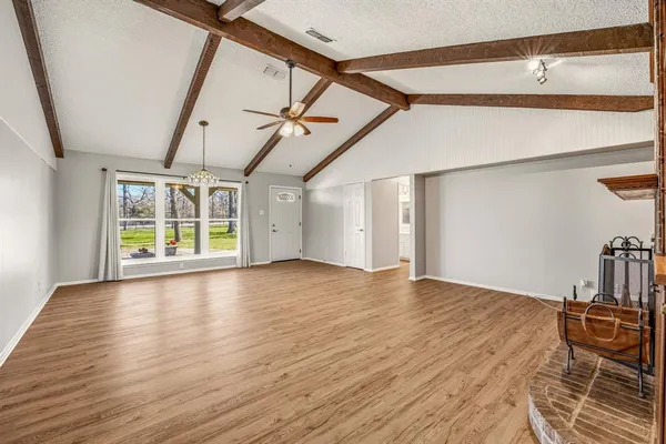 a view of empty room with wooden floor and fan