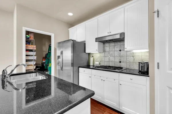 a kitchen with granite countertop a sink a stove and refrigerator