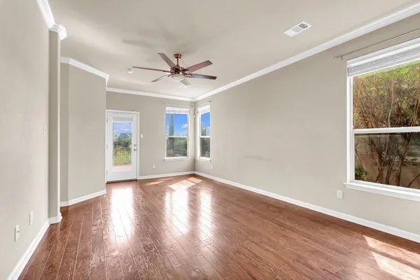 a view of empty room with wooden floor and fan