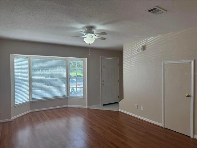 a view of an empty room with a window and wooden floor