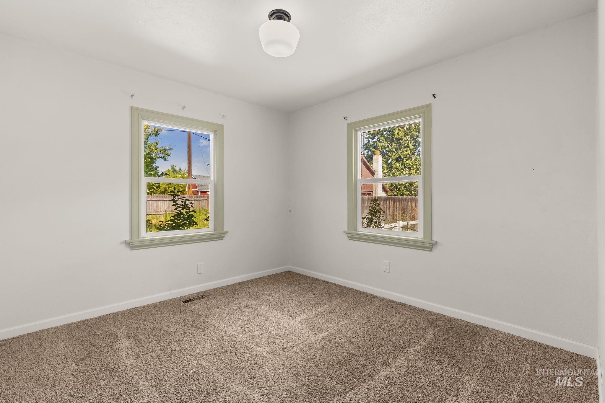 928 3rd Street Clarkston, WA 99403 - Photo 23 of 44 Carpeted room with two windows featuring light green trim, white walls, and a ceiling-mounted light fixture