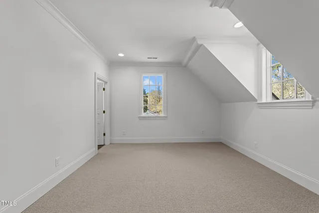 a view of an empty room with wooden floor and kitchen