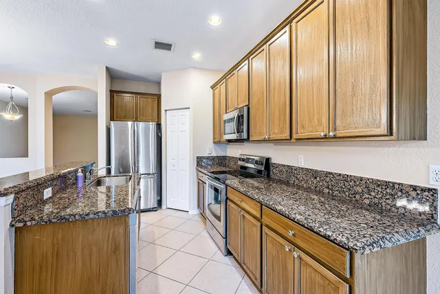 a kitchen with stainless steel appliances granite countertop a sink a stove and a wooden cabinets