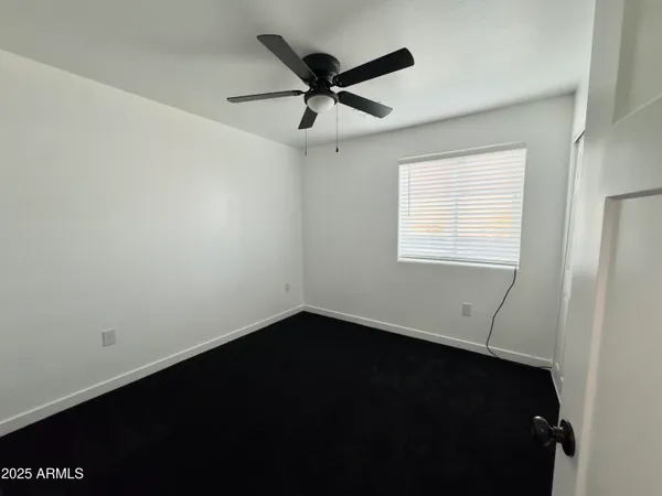 an empty room with a window and a ceiling fan