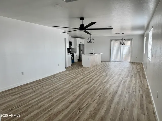 en empty room with wooden floor ceiling fan and window