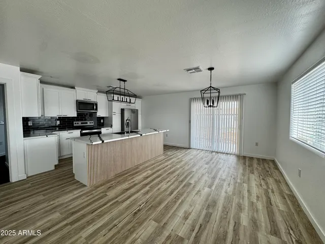 a kitchen with granite countertop a stove top oven a sink dishwasher and a refrigerator with wooden floor