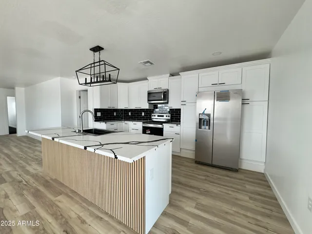 a kitchen with stainless steel appliances a refrigerator a stove a sink cabinets and wooden floor