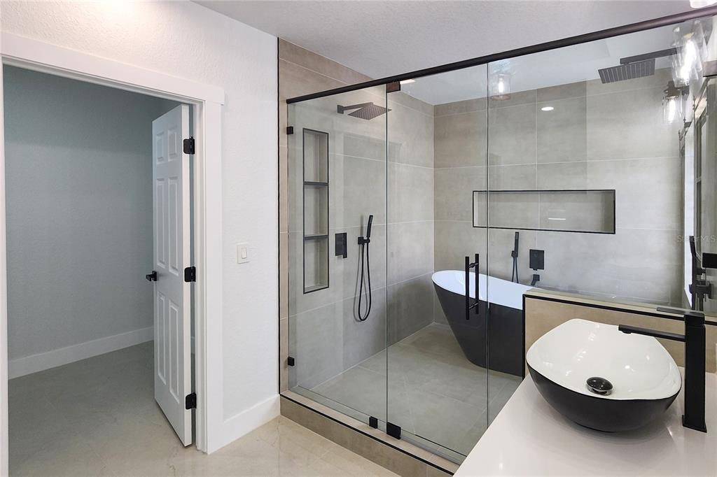 7027 Frascati Loop Wesley Chapel, FL 33544 - Photo 18 of 28 a bathroom with a tub shower and mirror