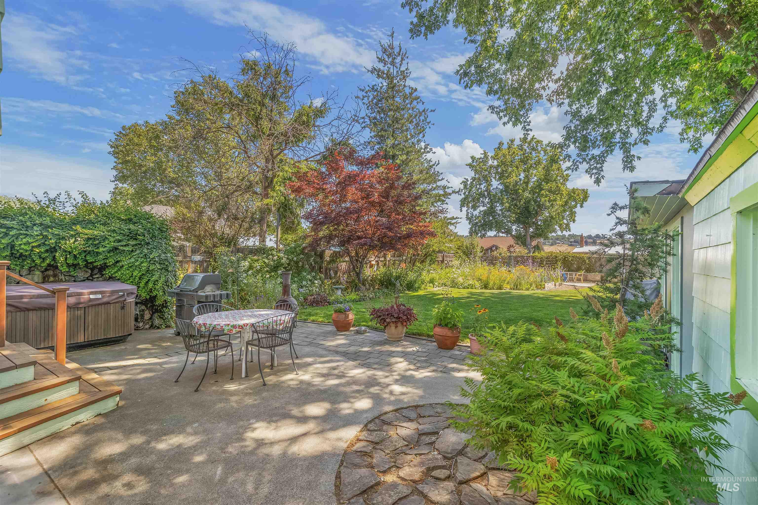 924 N Street Lewiston, ID 83501 - Photo 44 of 46 Expansive backyard featuring a concrete patio, a stone-edged garden bed, a manicured lawn, and mature trees