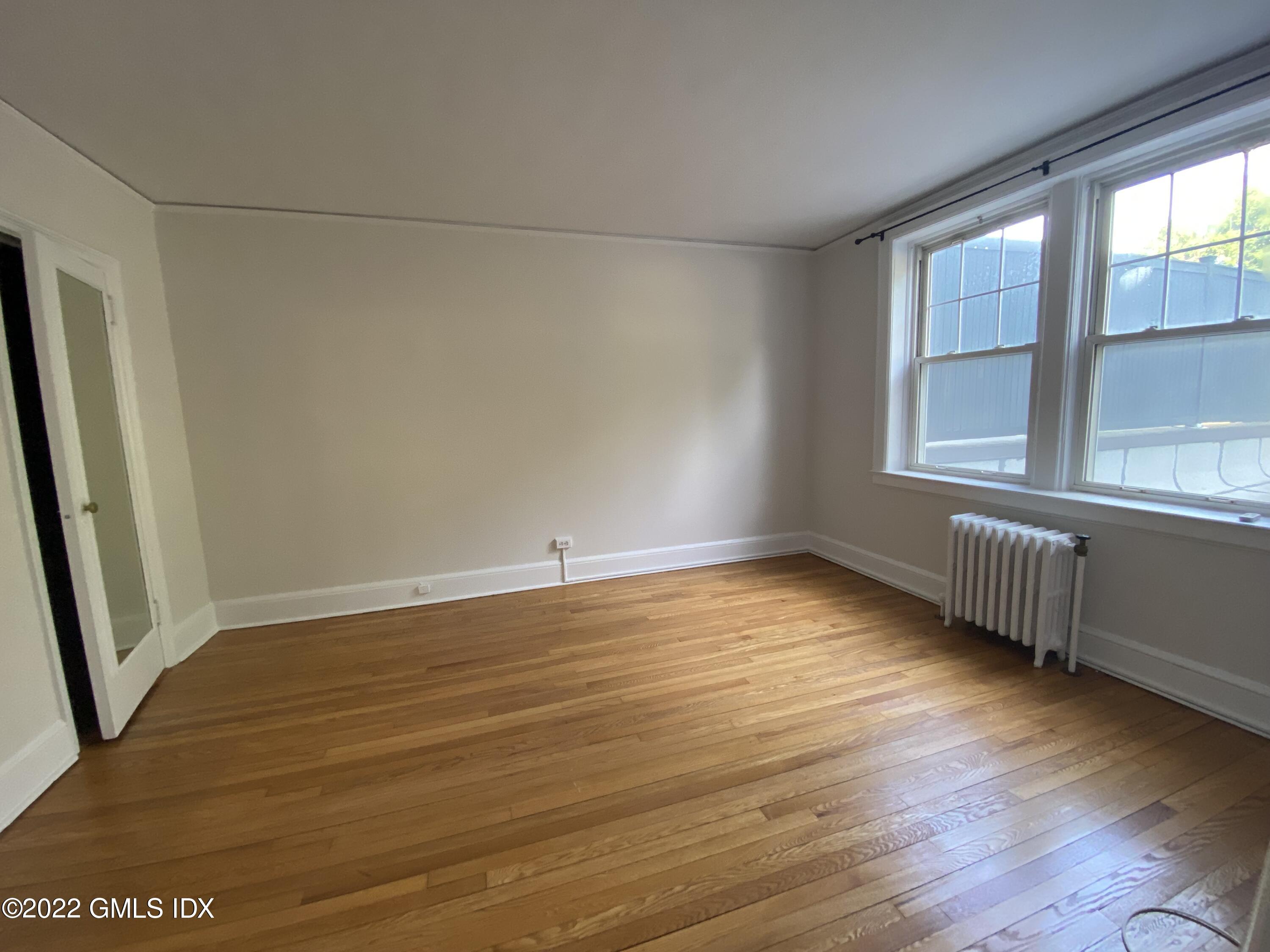 169 Mason Street, Unit 1F Greenwich, CT 06830 - Photo 13 of 14 an empty room with wooden floor and windows