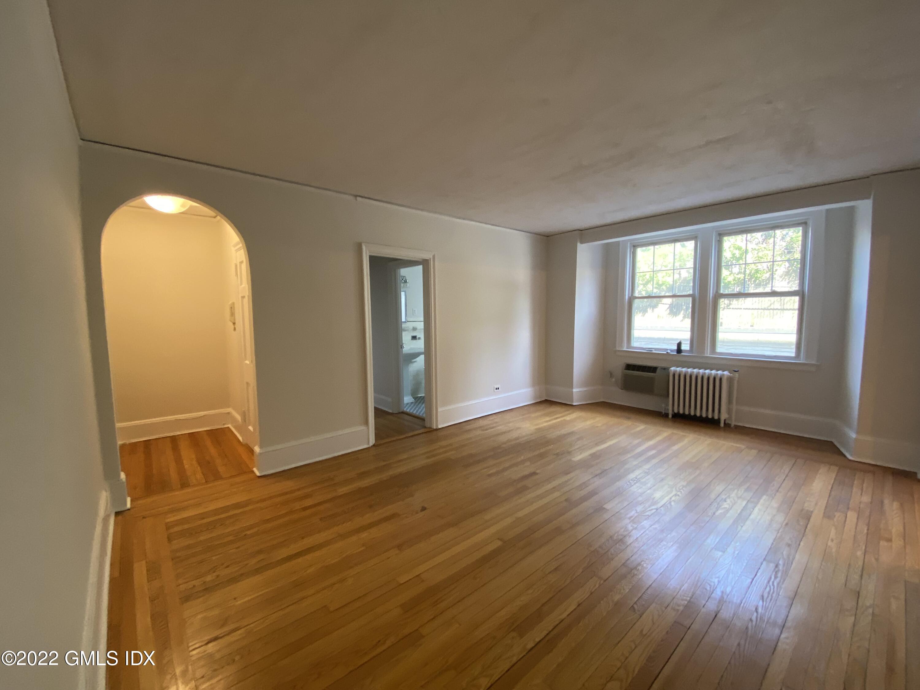 169 Mason Street, Unit 1F Greenwich, CT 06830 - Photo 4 of 14 a view of an empty room with wooden floor and a window