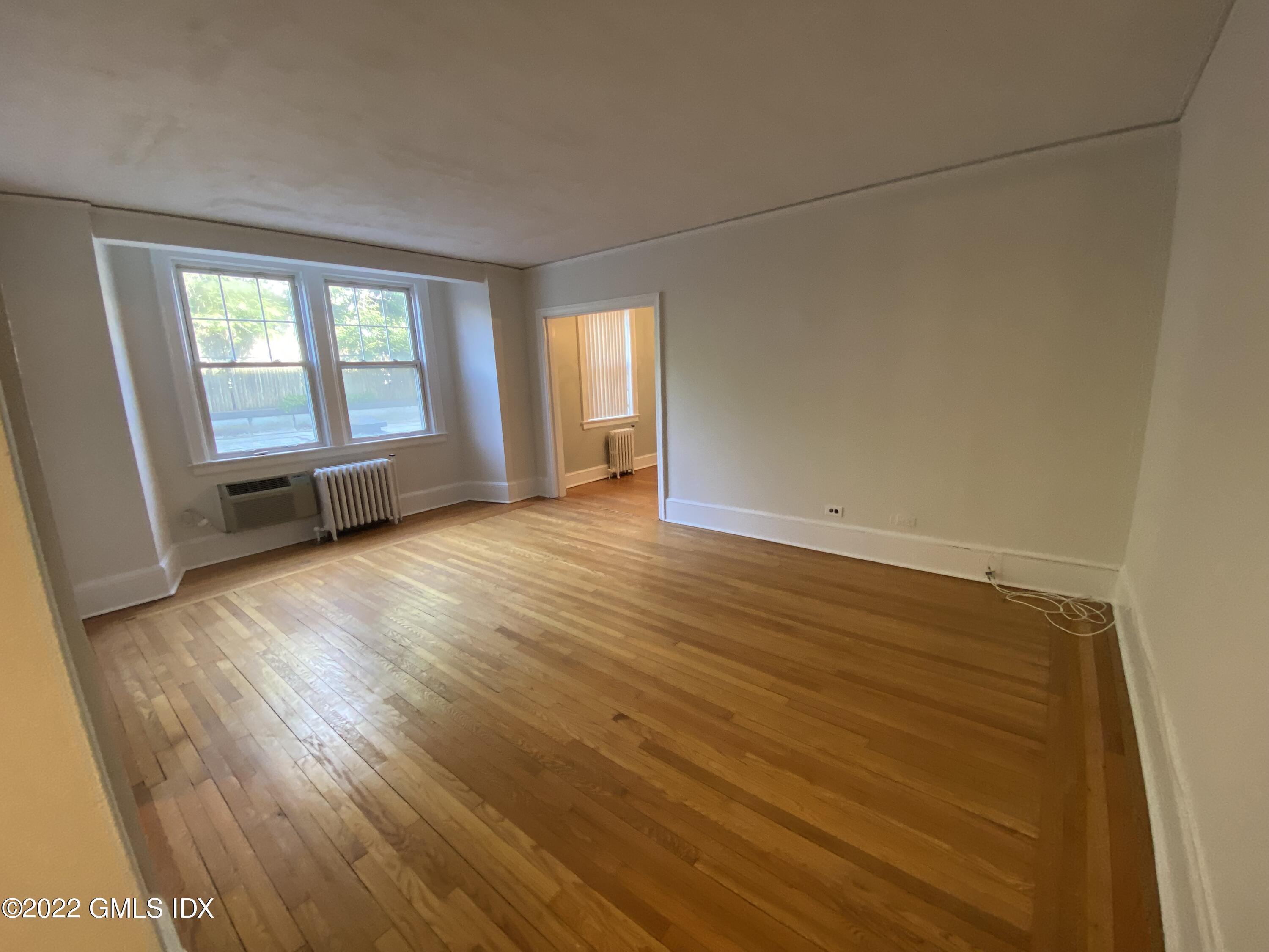 169 Mason Street, Unit 1F Greenwich, CT 06830 - Photo 5 of 14 an empty room with wooden floor and windows