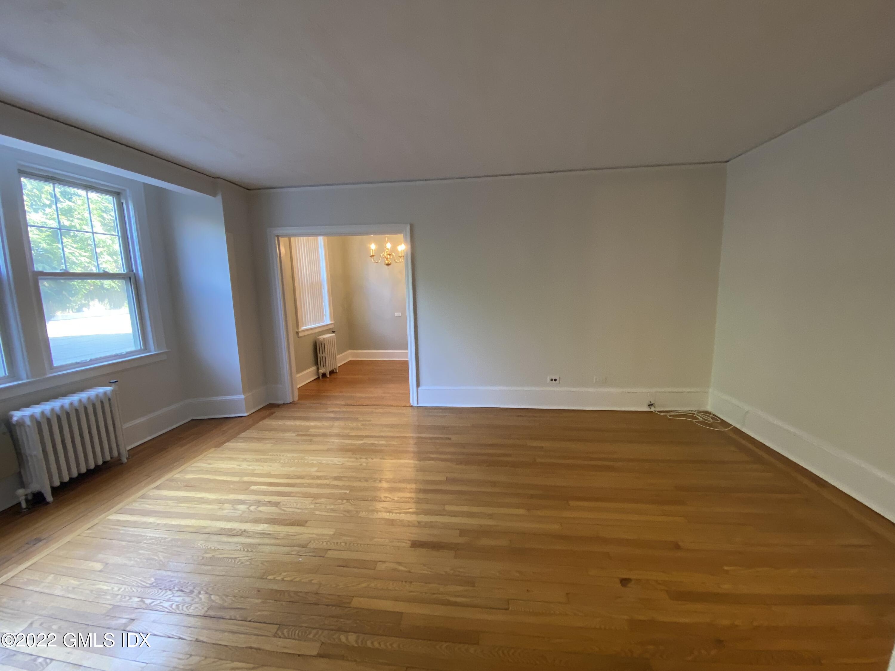 169 Mason Street, Unit 1F Greenwich, CT 06830 - Photo 6 of 14 a view of an empty room with window and wooden floor