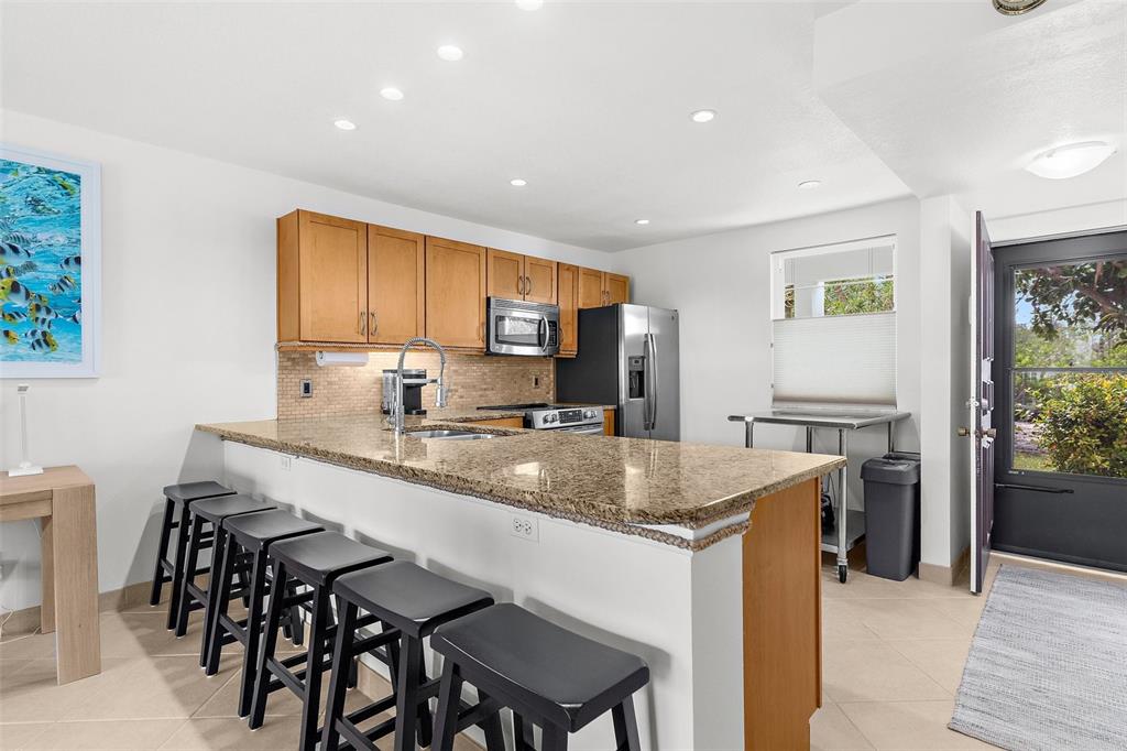 600 Sutton Place, Unit 101B Longboat Key, FL 34228 - Photo 11 of 53 a kitchen with a stove a sink a dining table and chairs