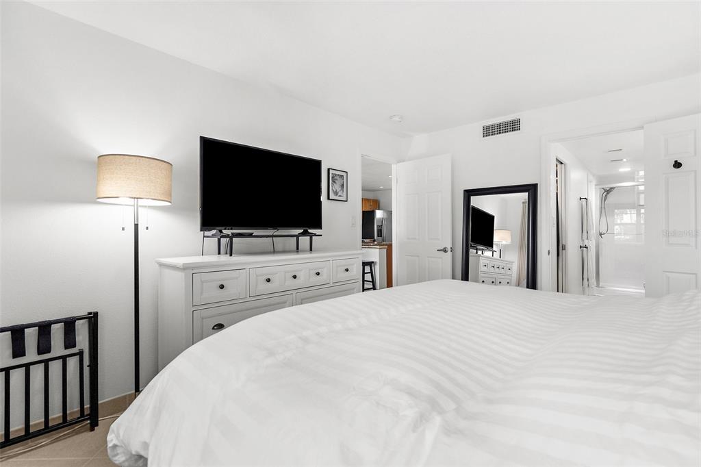 600 Sutton Place, Unit 101B Longboat Key, FL 34228 - Photo 13 of 53 a view of a bedroom with flat screen tv and dresser
