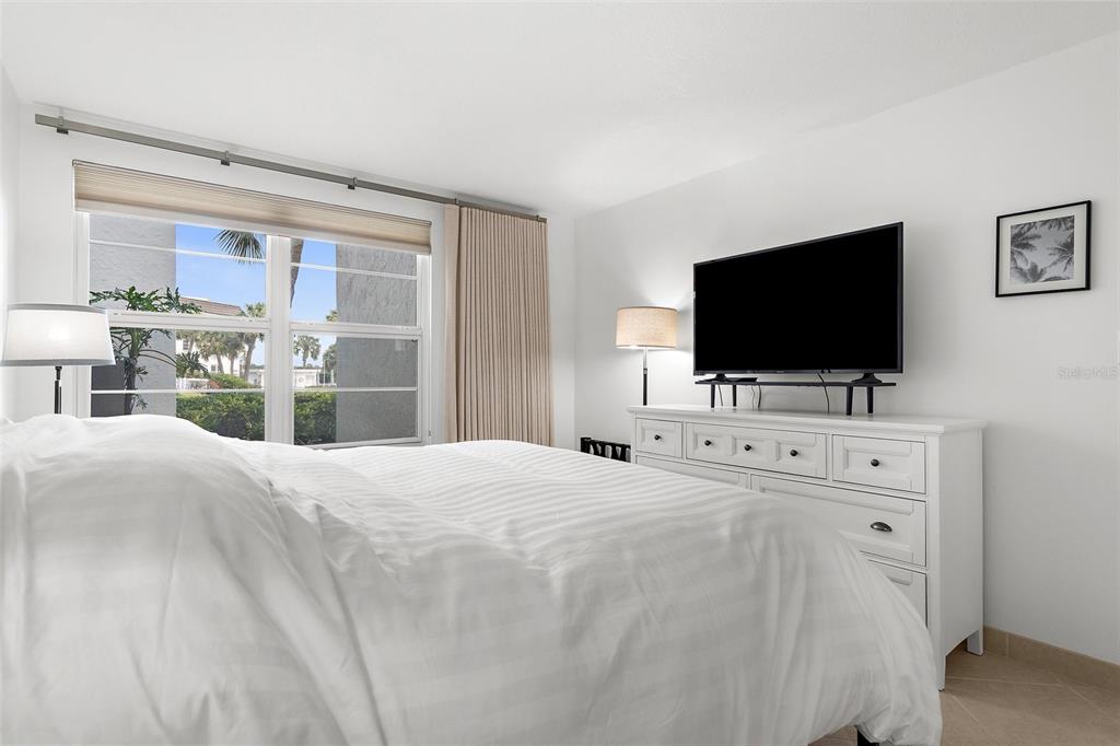 600 Sutton Place, Unit 101B Longboat Key, FL 34228 - Photo 14 of 53 a bedroom with a bed and a flat tv screen in it