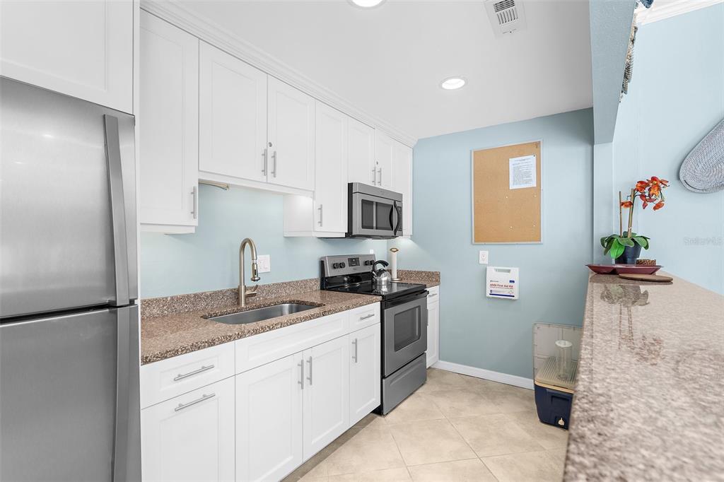 600 Sutton Place, Unit 101B Longboat Key, FL 34228 - Photo 35 of 53 a kitchen with stainless steel appliances granite countertop a refrigerator sink and stove