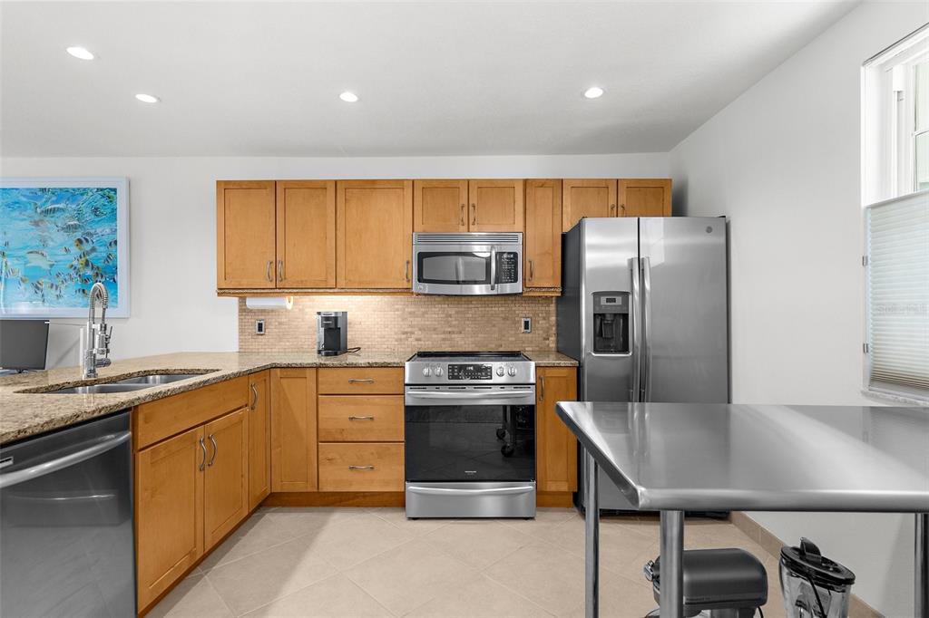 600 Sutton Place, Unit 101B Longboat Key, FL 34228 - Photo 10 of 53 a kitchen with stainless steel appliances granite countertop a stove a refrigerator a sink a stove and island