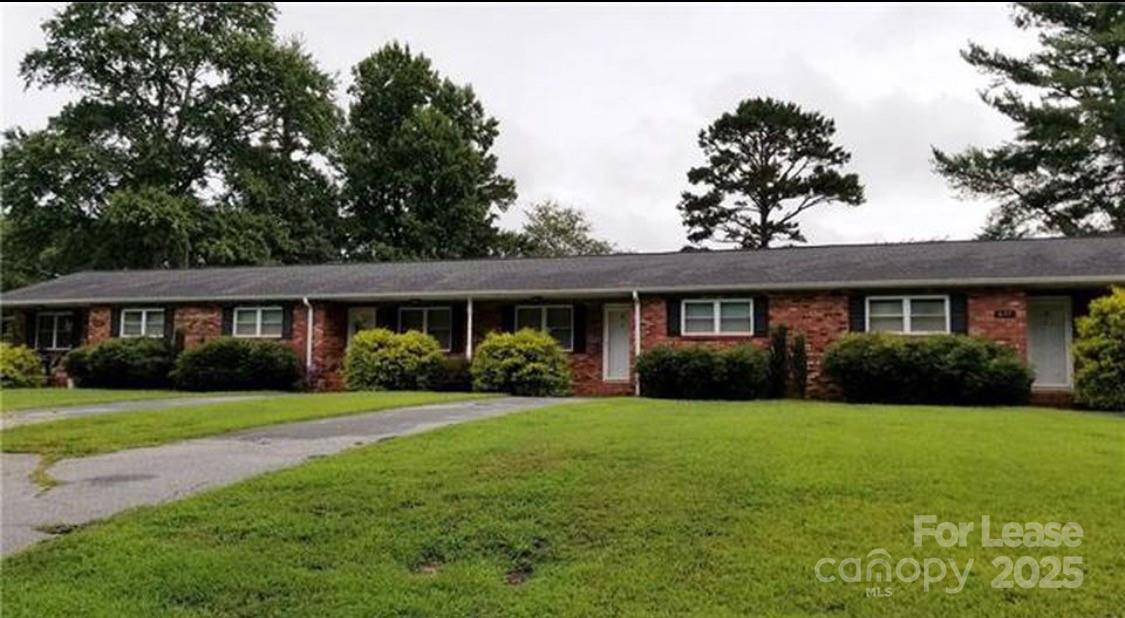 a view of a brick house with a big yard and potted plants