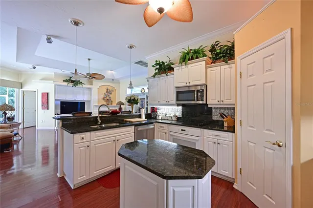 a kitchen with granite countertop a sink a counter top space appliances and cabinets