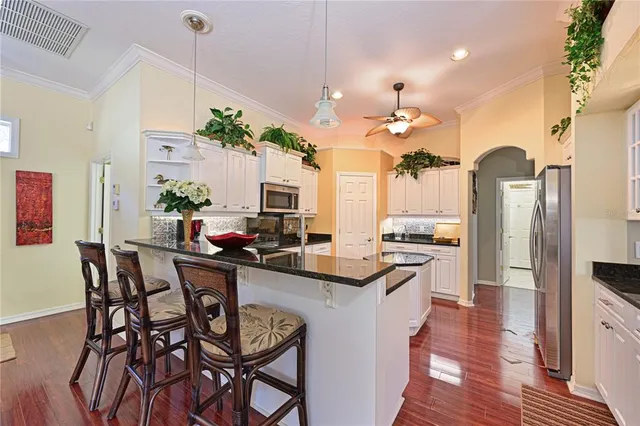 a kitchen with stainless steel appliances kitchen island granite countertop a table chairs and a refrigerator