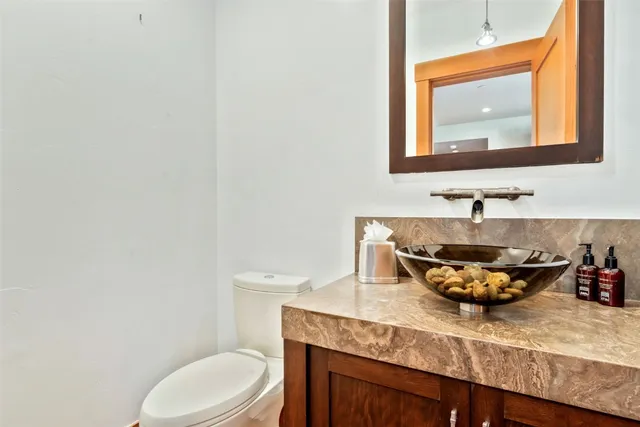 a bathroom with a granite countertop toilet sink and mirror