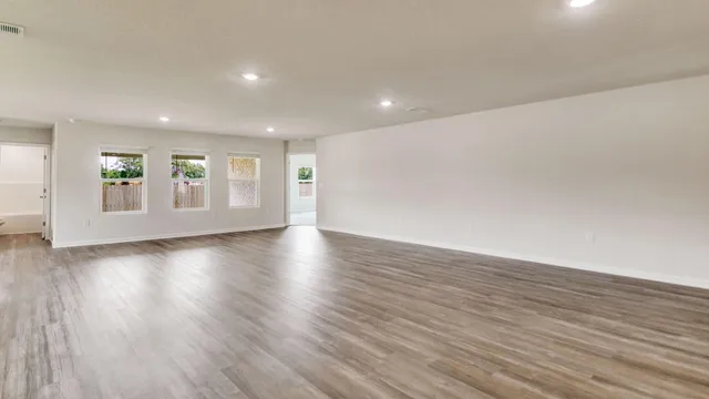 a view of an empty room with wooden floor and windows