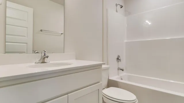 a bathroom with a bathtub shower sink vanity mirror and toilet