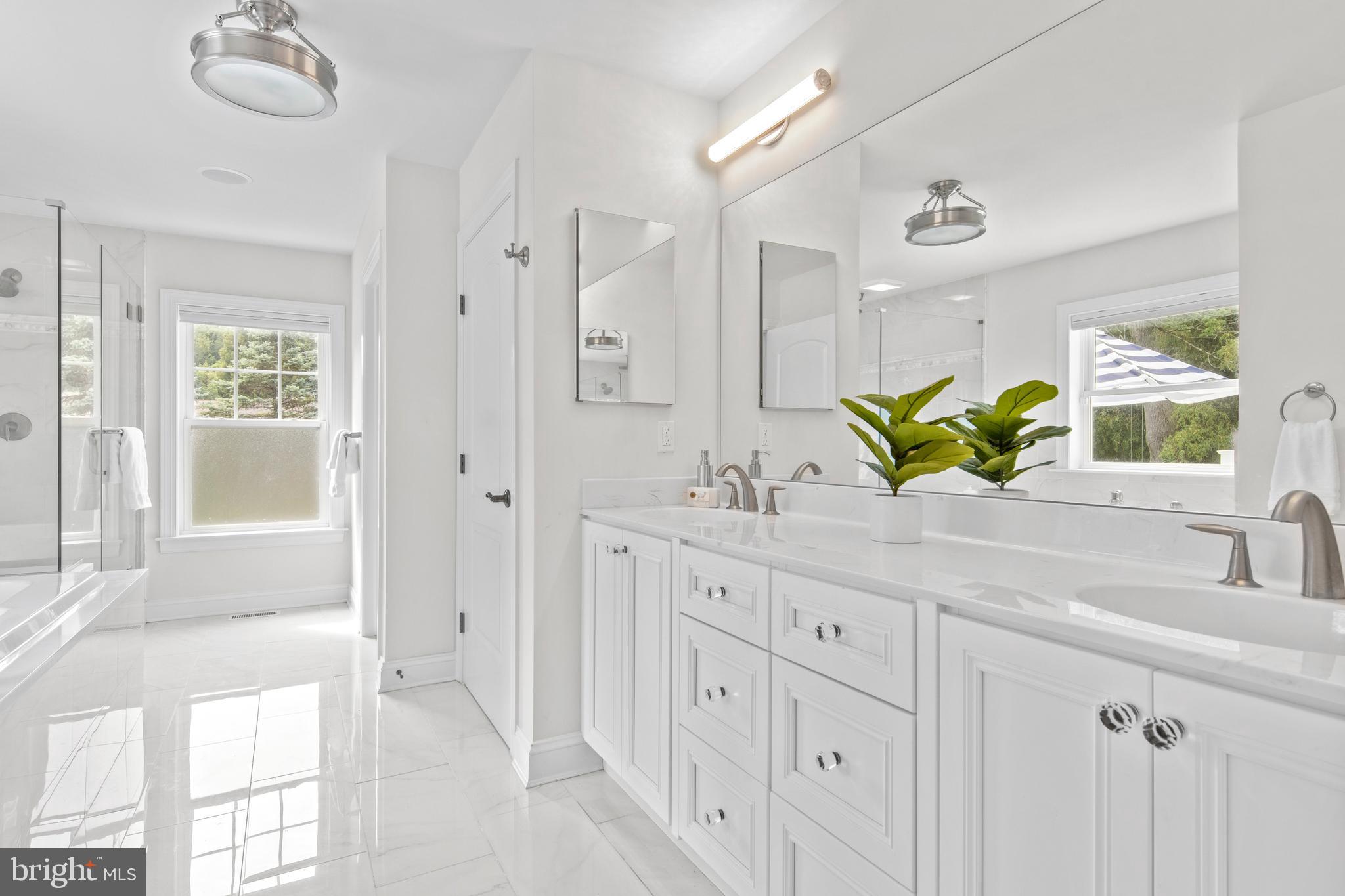 444 Conestoga Road Wayne, PA 19087 - Photo 44 of 82 a bathroom with a double vanity sink a mirror a bathtub and next to a window