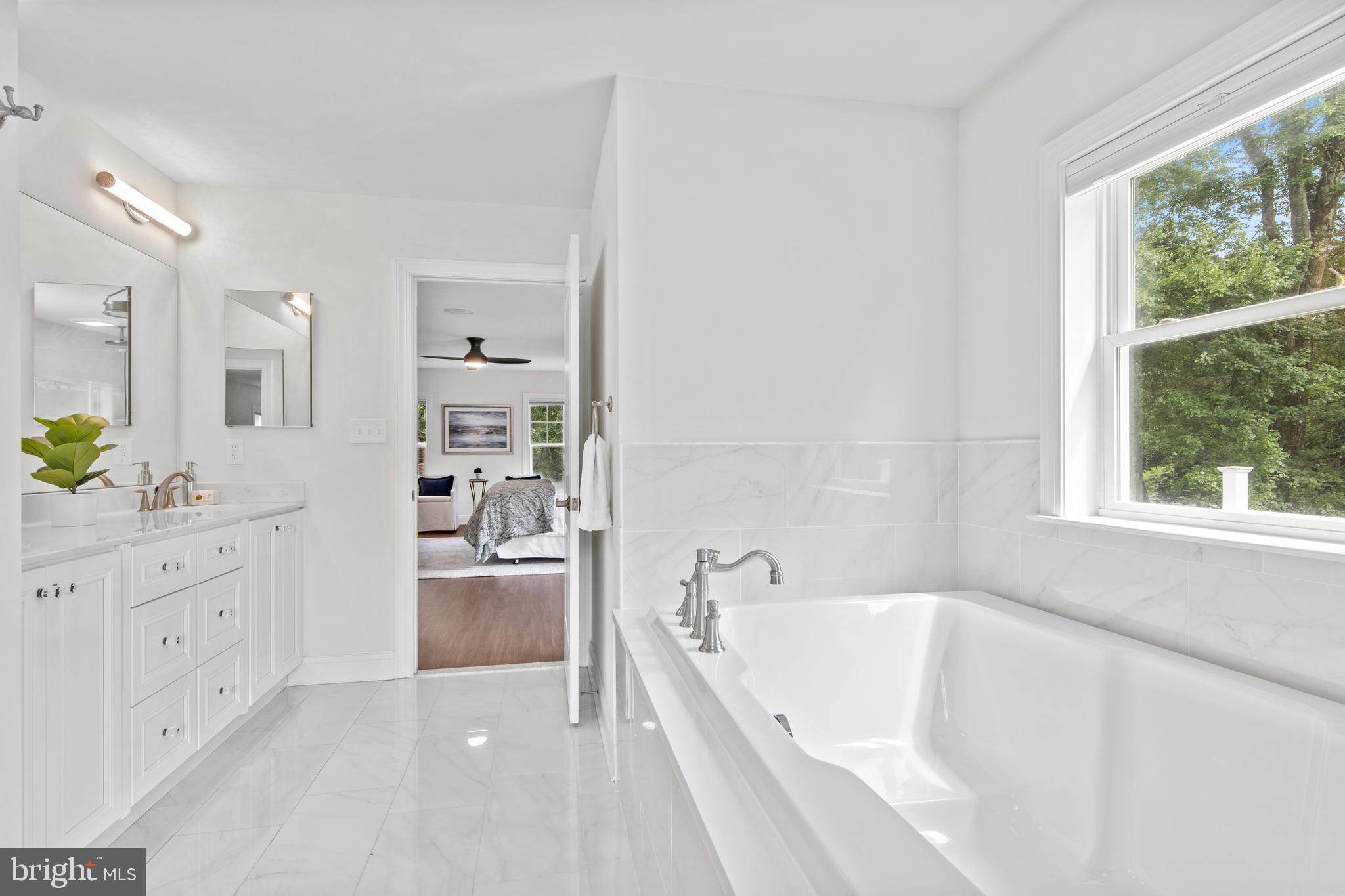 444 Conestoga Road Wayne, PA 19087 - Photo 47 of 82 a bathroom with a bathtub a sink a window and a mirror