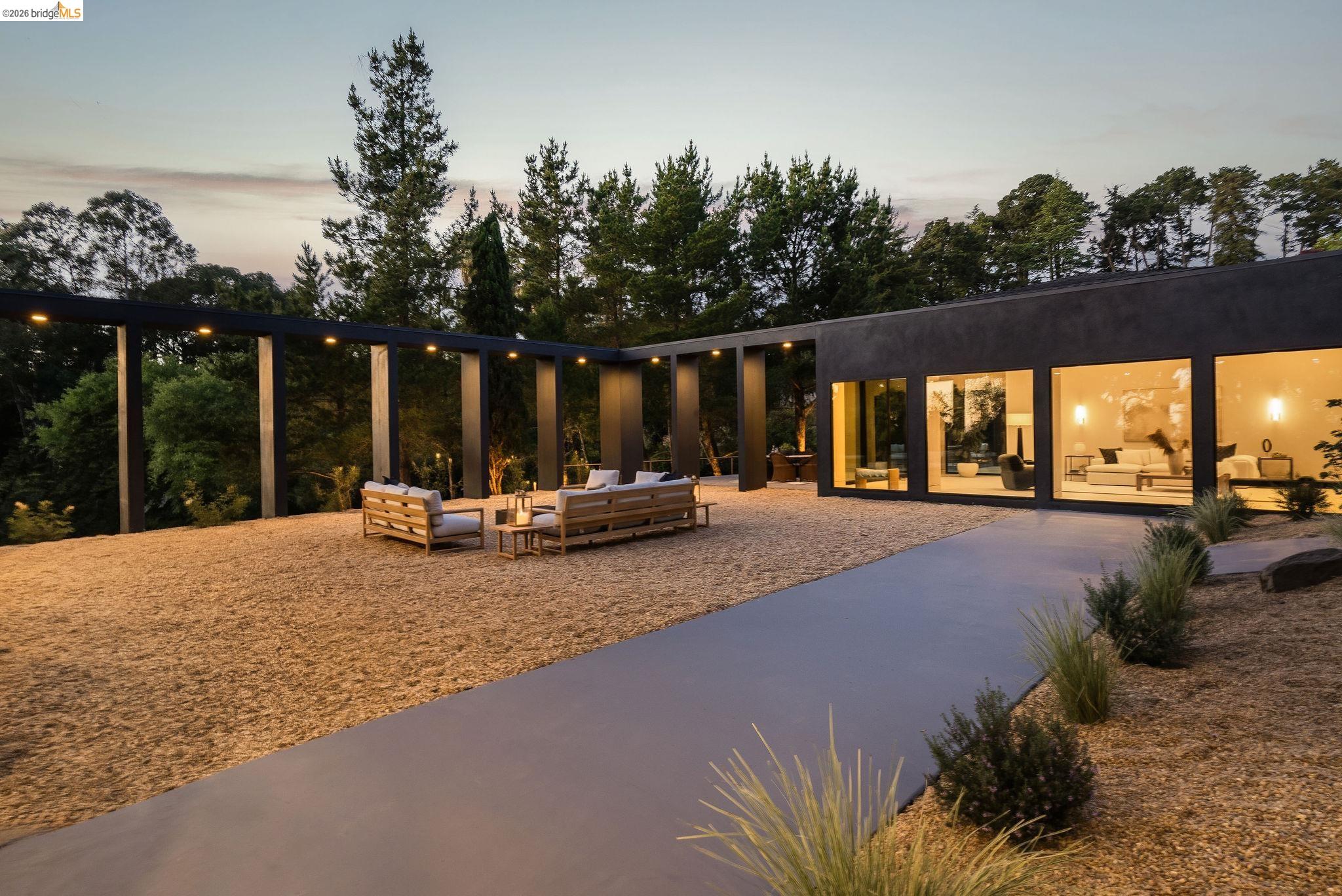 5645 Bacon Road Oakland, CA 94619 - Photo 76 of 94 Modern single-story exterior featuring a dark facade with expansive windows, a gravel patio, and a covered pergola with integrated lighting