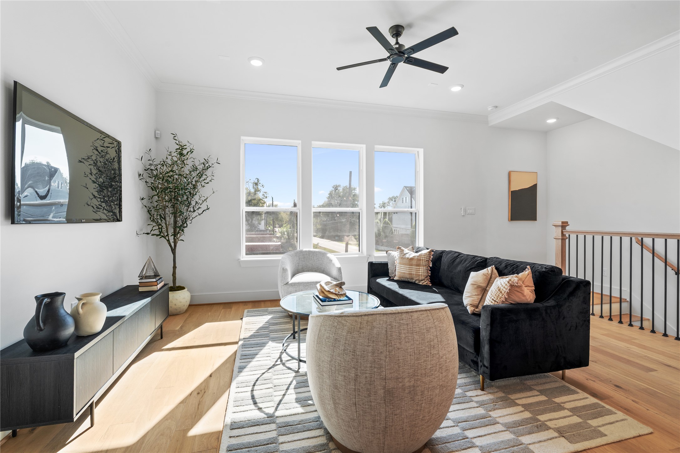 1614 Ojeman Road, Unit J Houston, TX 77055 - Photo 12 of 50 Stairs from the first floor lead into this bright and inviting living room featuring large windows, hardwood floors, and recessed lighting - perfect for relaxing or entertaining.