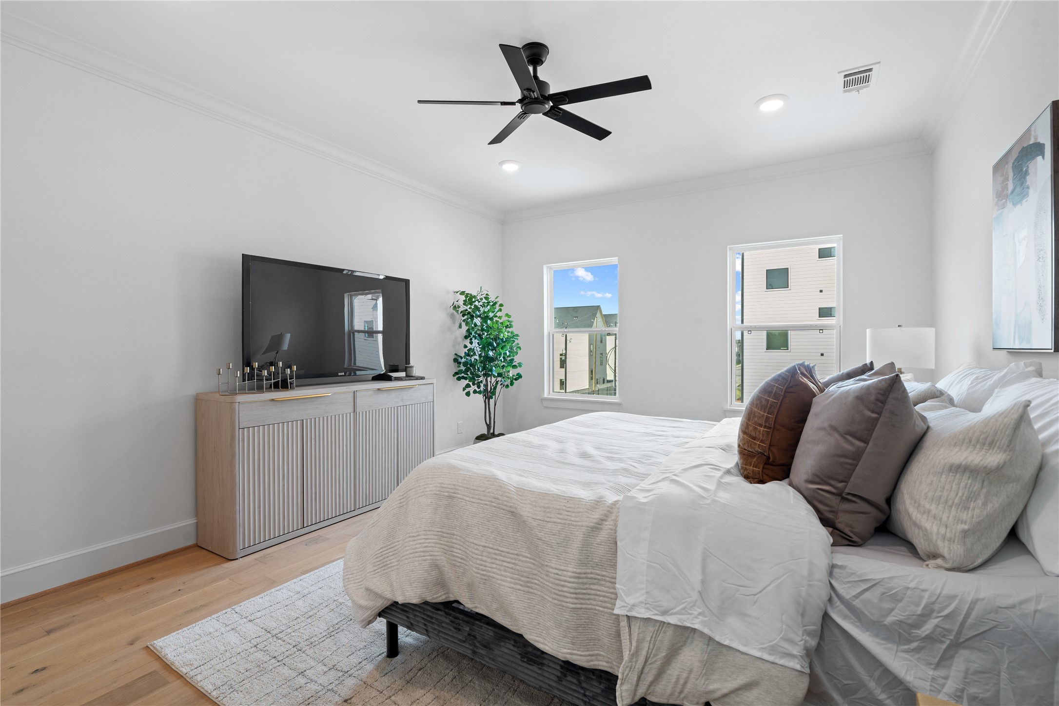 1614 Ojeman Road, Unit J Houston, TX 77055 - Photo 33 of 50 This generous third-floor primary suite showcases a king-sized bed and a stylish media setup, offering a luxurious balance of comfort, function, and modern design.